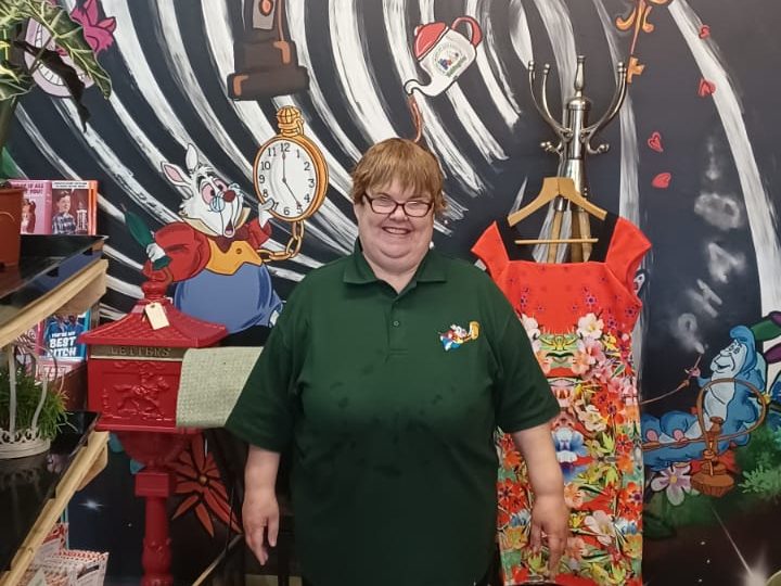 Picture of Anita stood at work with a colourful background behind her